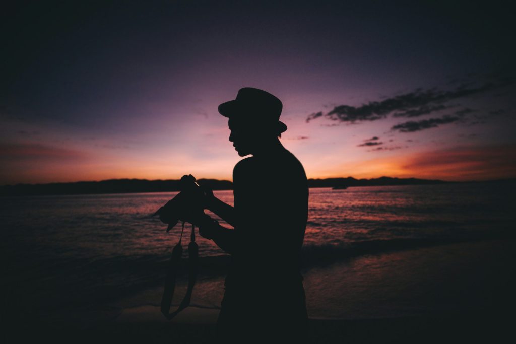 silhouette photography of man standing while holding DSLR camera