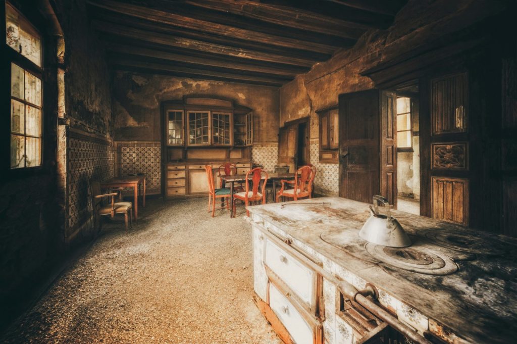 Abandoned rustic kitchen with old stove and chairs