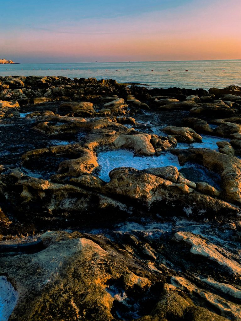 a rocky beach with water and a sunset