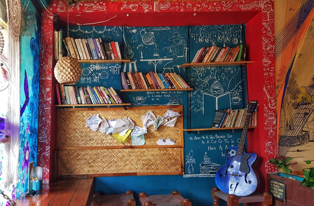 Colorful room with bookshelves, guitar, and artistic decorations creating a cozy atmosphere.